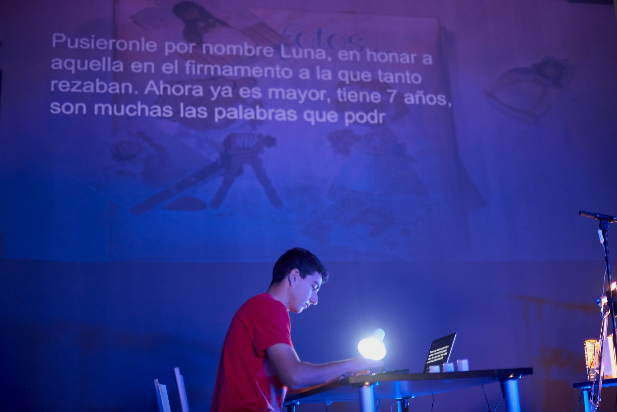 A young man practicing live writing, his text projected on the wall.