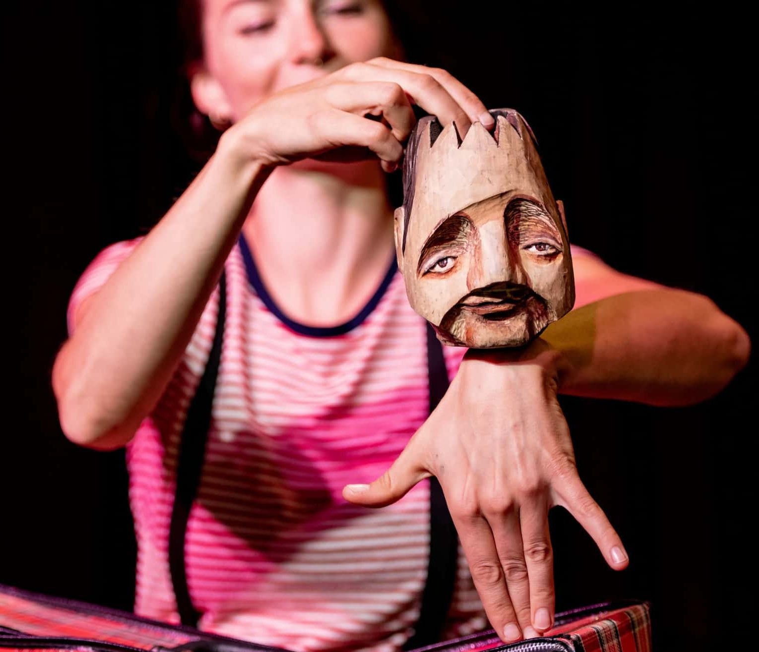 Fotografi: Bildet viser en skuespiller som holder frem en dukke med et ansikt laget av tre. Kroppen til dukken består av hånden til skuespilleren.