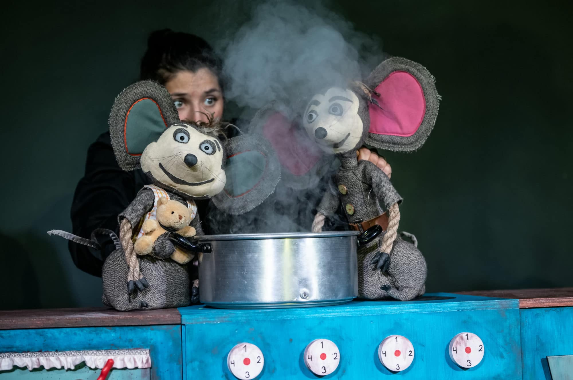 Fotografi: Bildet viser en forestilling der en kvinnelig skuespiller fremfører dukketeater med to dukker som illustrerer mus.